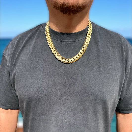 Man wearing a 18mm 24 inch miami cuban link gold chain necklace with a blue sky background